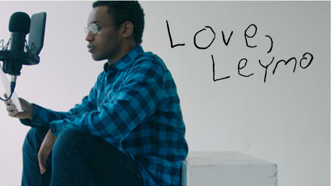 Un jeune homme noir vêtu d'une chemise à carreaux bleue est assis et parle dans un micro. Les mots « Love, Leymo » sont écrits à la main sur le mur à côté de lui.