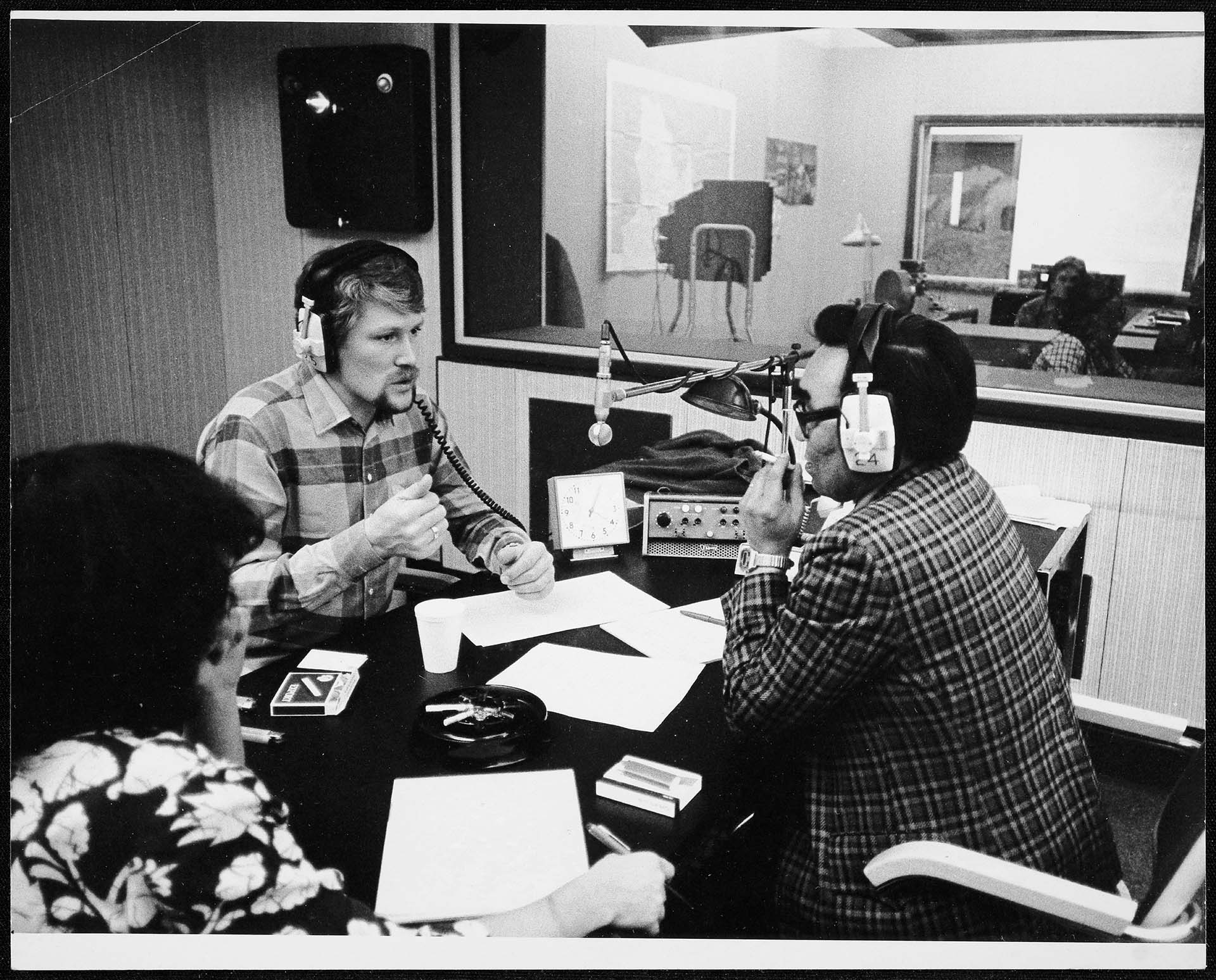 In a radio studio, an assistant, a host and a guest are recording a program.